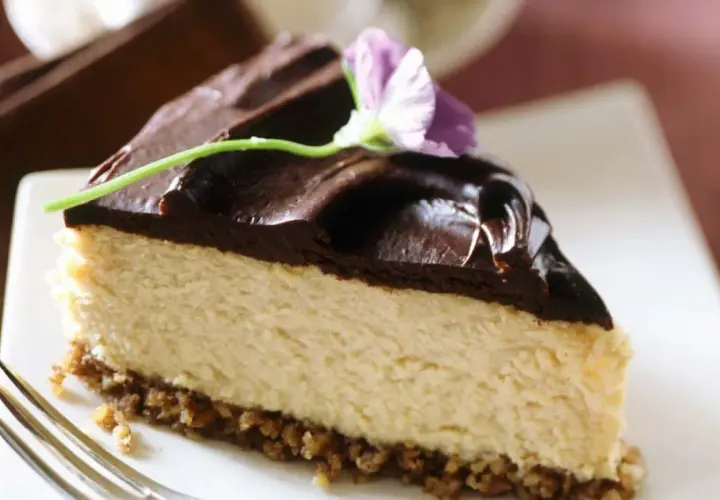 Deliciosa tarta de queso y chocolate, con una capa cremosa y cobertura brillante, decorada con una flor.