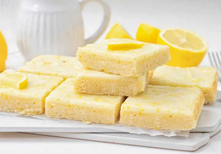 Deliciosos brownie de limón, con una capa superior glaseada y ralladura de limón.