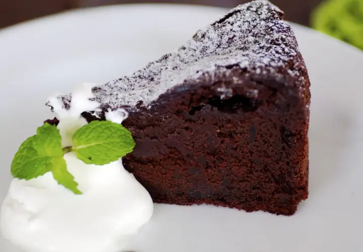 Un trozo de bizcocho de chocolate esponjoso con yogur y menta, espolvoreado con azúcar glas.