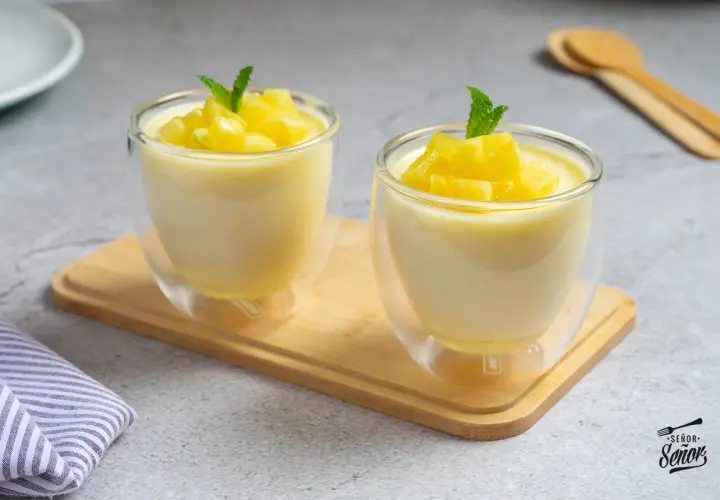 Dos copas de cristal con un delicioso mousse de piña, decoradas con trocitos de piña y menta.