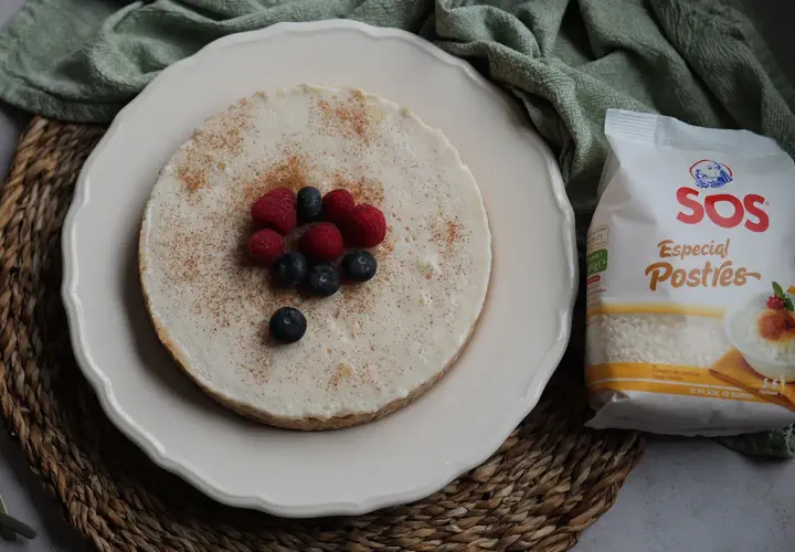 Deliciosa tarta de arroz, cubierta con canela y decorada con frambuesas y arándanos. A su lado, un paquete de arroz SOS Especial Postres.