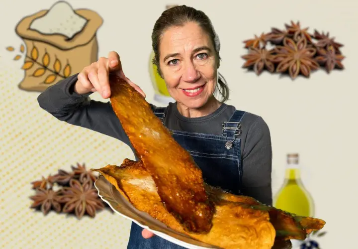 Mujer sonriente muestra una coca de vidre dorada y crujiente, con ingredientes como harina, anís estrellado y aceite de oliva de fondo.