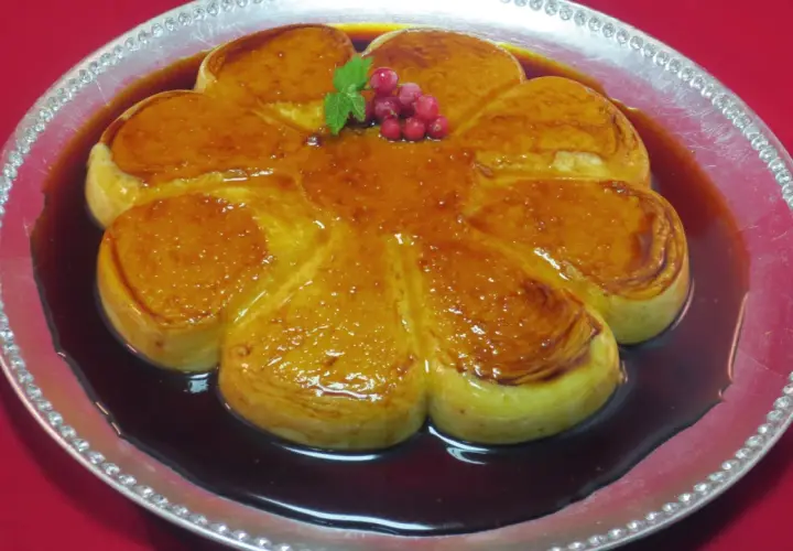 Delicioso flan de arroz con leche con caramelo dorado, decorado con bayas rojas y menta.