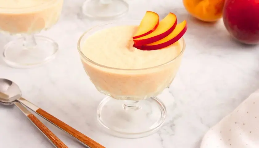 Delicioso mousse de melocotón en copas de cristal, decorado con finas láminas de melocotón.