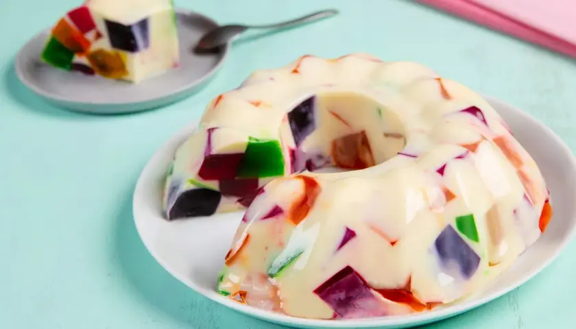 Gelatina con leche condensada, con trozos de colores vibrantes incrustados, como un mosaico dulce.