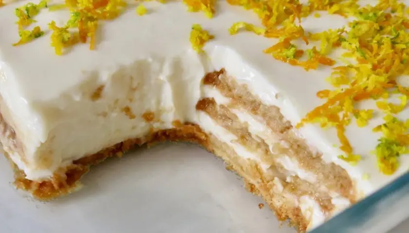 Tarta de limón sin horno, con capas de galleta y crema, decorada con ralladura de limón y naranja.