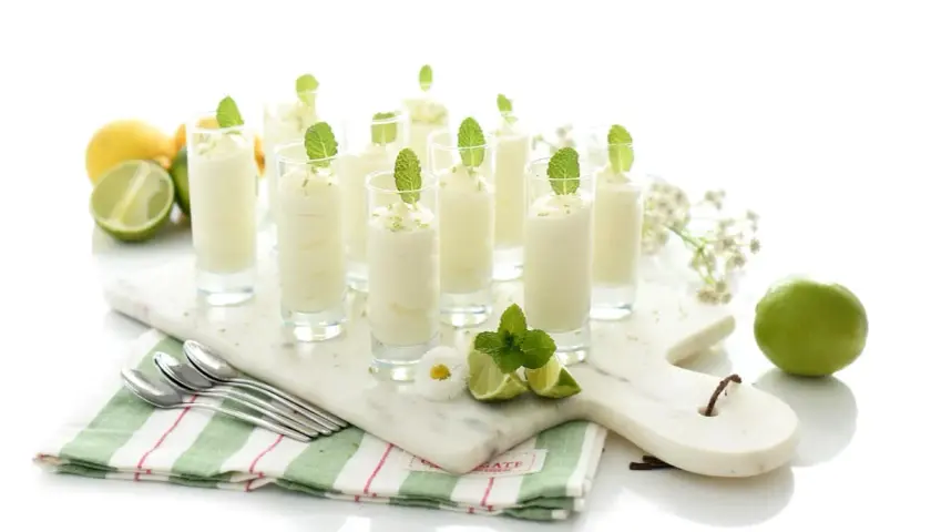 Delicioso mousse de limón en vasitos, decorado con menta y ralladura de limón. Frescura y sabor en cada bocado.