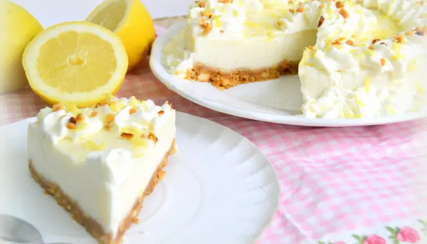 Deliciosa tarta de limón con cuajada y leche condensada, decorada con nata y ralladura de limón.