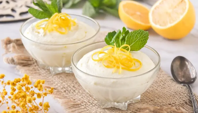 Delicioso mousse de limón con leche condensada, decorado con ralladura de limón y menta fresca.