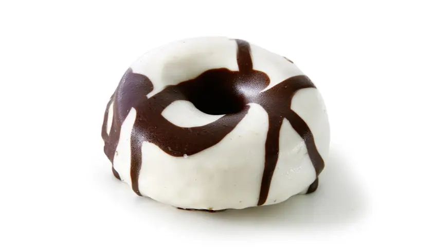 Un delicioso donut de chocolate blanco con un glaseado blanco y un diseño de chocolate negro que cae en cascada.