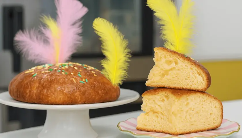 Pan dulce decorado con plumas de colores y chispas, ideal para una receta mona de pascua.