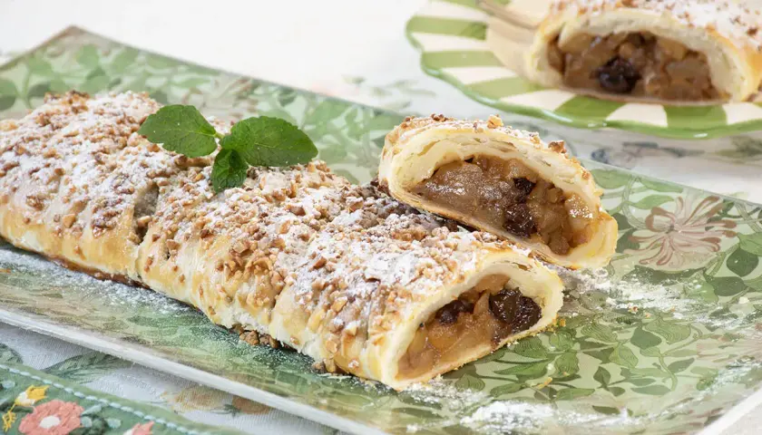 Deliciosa trenza de hojaldre rellena de manzana y pasas, espolvoreada con azúcar glas y nueces picadas.
