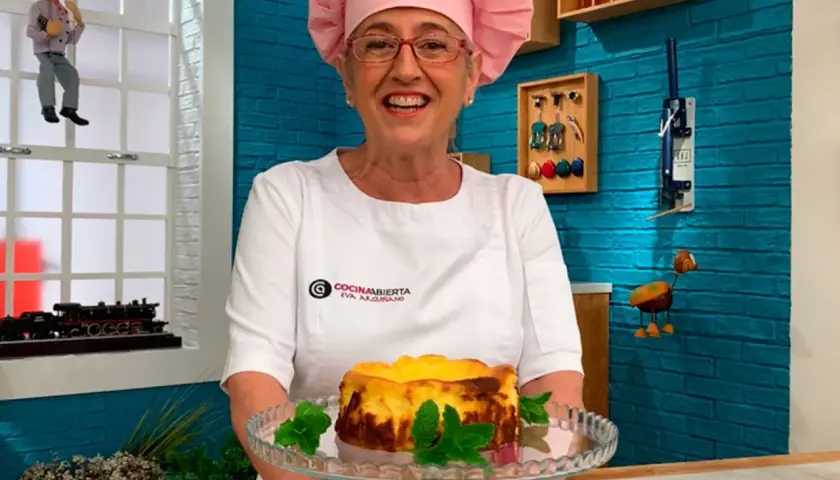 Eva Arguiñano sonríe mostrando una deliciosa tarta de queso casera, decorada con menta fresca.