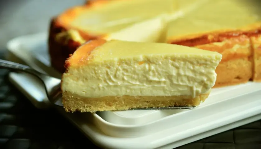 Una rebanada cremosa de tarta de queso Philadelphia, con su base dorada y relleno suave, lista para ser disfrutada.