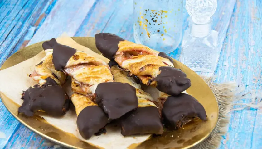 Deliciosos lazos de hojaldre con relleno de fresa, bañados en chocolate negro. Un dulce tentempié perfecto.
