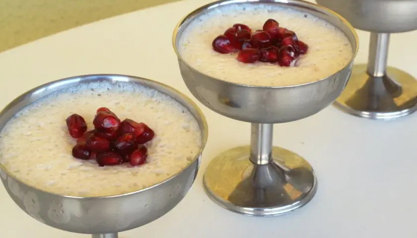 Delicioso mousse de leche condensada Thermomix, coronado con granada, servido en copas metálicas.