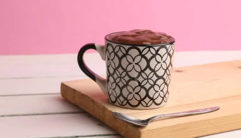 Taza con un delicioso oreo mug cake, lista para disfrutar con una cuchara.