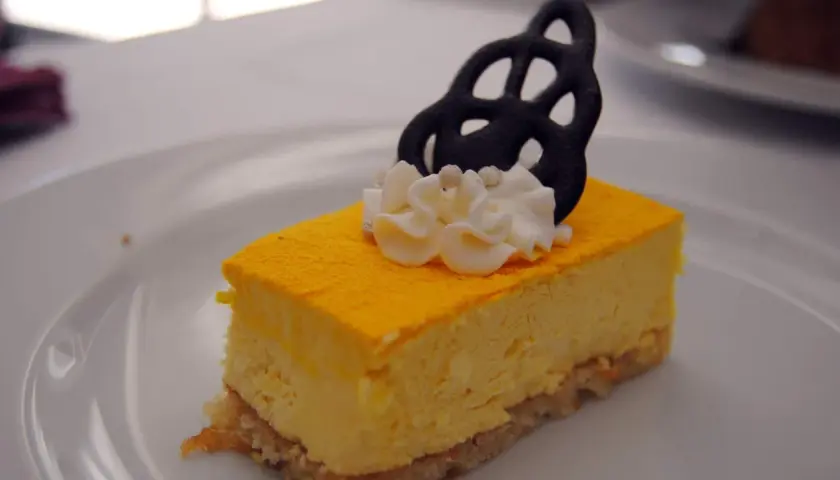 Deliciosa tarta de mango con crema batida y un adorno negro.