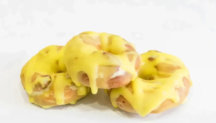 Tres rosquillas de San Isidro cubiertas con un glaseado amarillo brillante, listas para disfrutar.