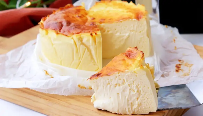 Tarta de queso en freidora de aire, dorada y cremosa, con una porción lista para disfrutar.