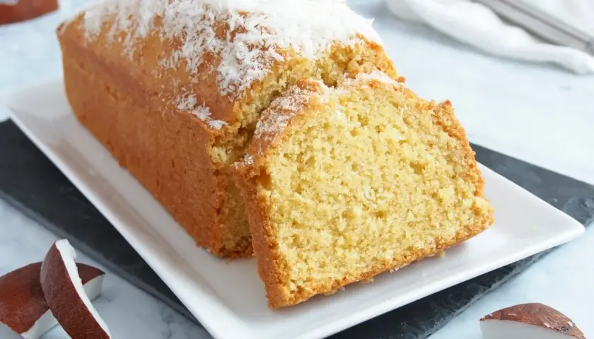 Bizcocho de coco esponjoso, cubierto con coco rallado y acompañado de trozos de coco fresco. ¡Un postre tropical delicioso!