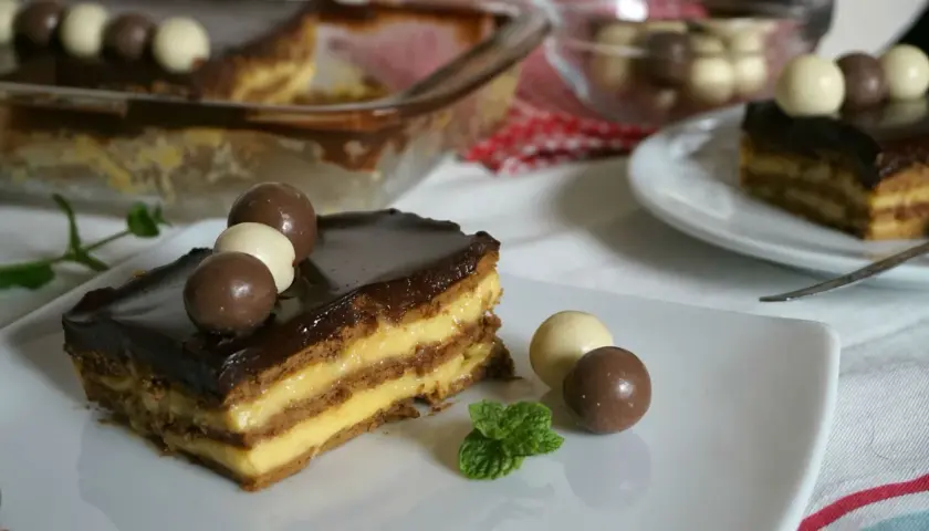 Tarta de la abuela con flanín, capas de galleta y crema, cubierta de chocolate y decorada con bombones. ¡Un postre casero irresistible!