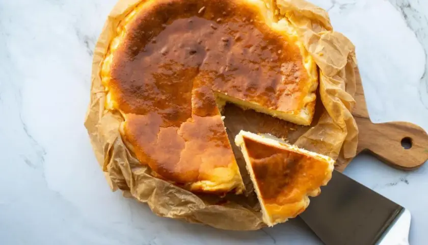 Tarta de queso congelada, dorada y cremosa, con una porción servida en una espátula.