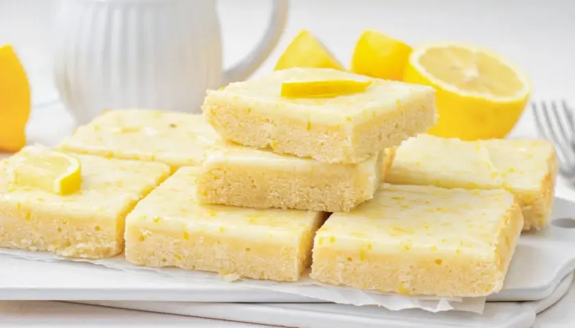 Deliciosos brownie de limón, con una capa superior glaseada y ralladura de limón.