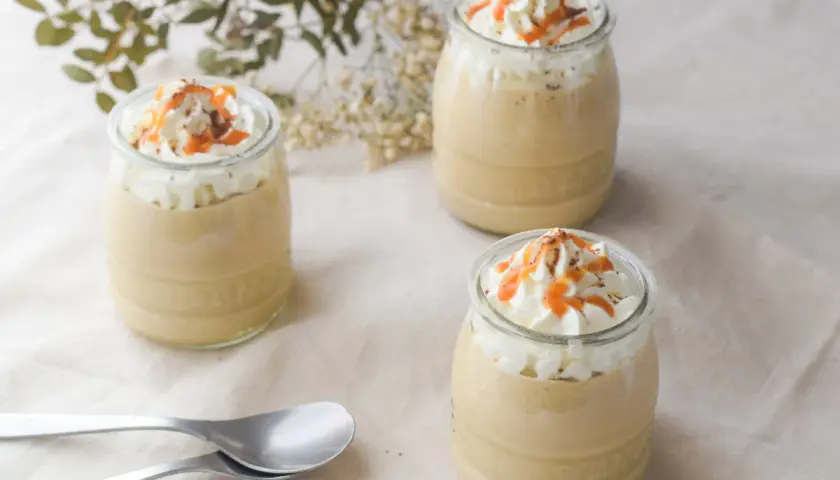 Delicioso mousse de café en vasitos, coronado con crema batida, caramelo y cacao. ¡Perfecto para un postre!