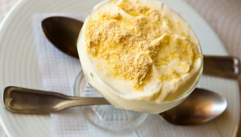 Delicioso postre de serradura portuguesa en copa, cubierto con migas de galleta.
