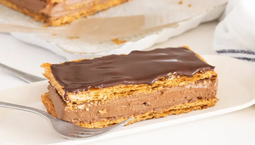 Delicioso milhojas de chocolate con capas crujientes de hojaldre y crema de cacao, listo para disfrutar.