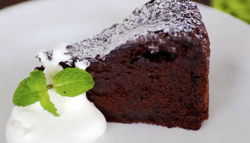 Un trozo de bizcocho de chocolate esponjoso con yogur y menta, espolvoreado con azúcar glas.