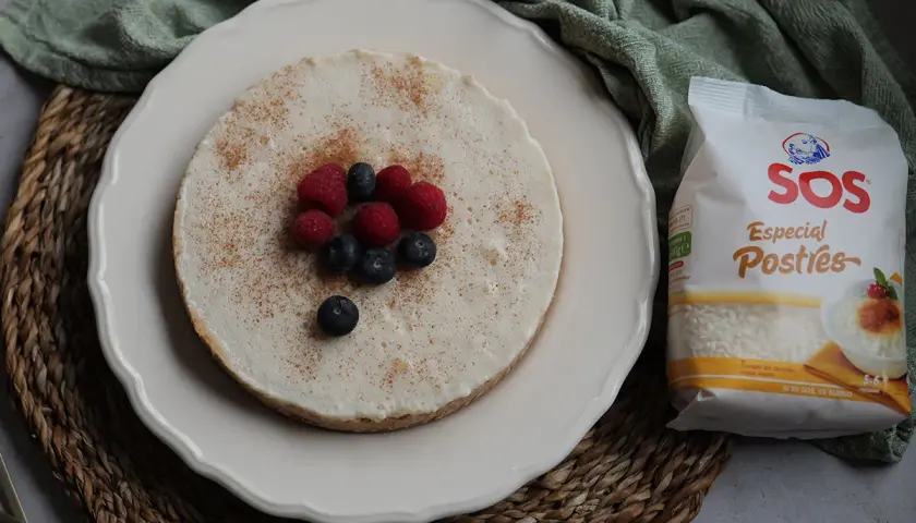 Deliciosa tarta de arroz, cubierta con canela y decorada con frambuesas y arándanos. A su lado, un paquete de arroz SOS Especial Postres.