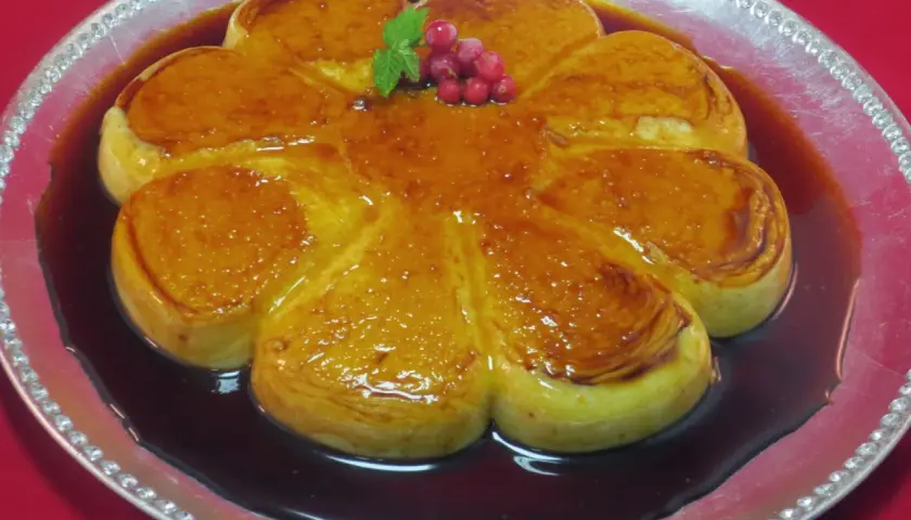 Delicioso flan de arroz con leche con caramelo dorado, decorado con bayas rojas y menta.
