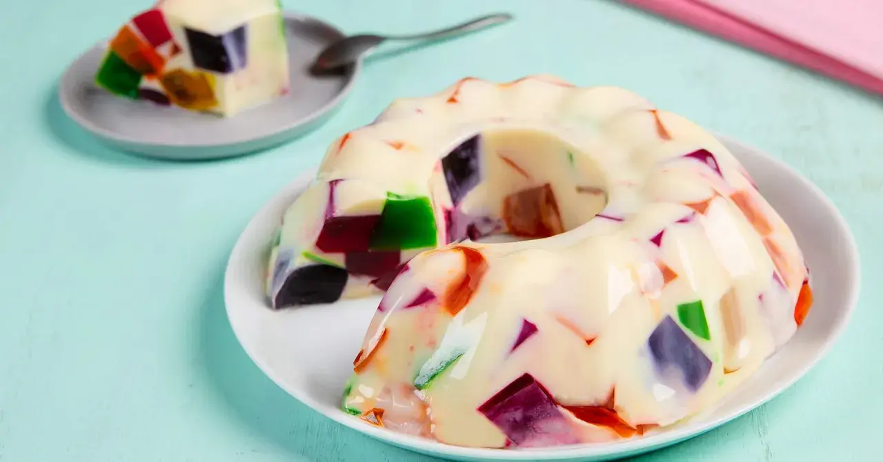 Gelatina con leche condensada, con trozos de colores vibrantes incrustados, como un mosaico dulce.