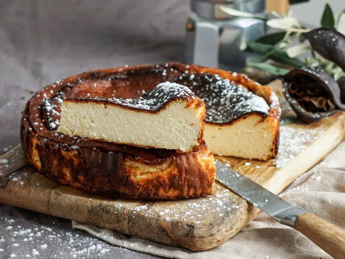 Tarta de queso la Viña, cremosa y dorada, con un toque de azúcar glas. Perfecta para disfrutar.