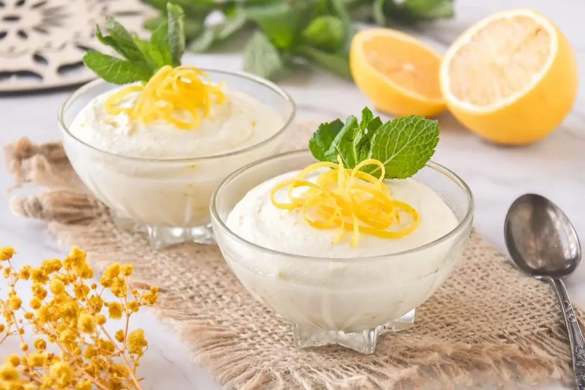 Delicioso mousse de limón con leche condensada, decorado con ralladura de limón y menta fresca.