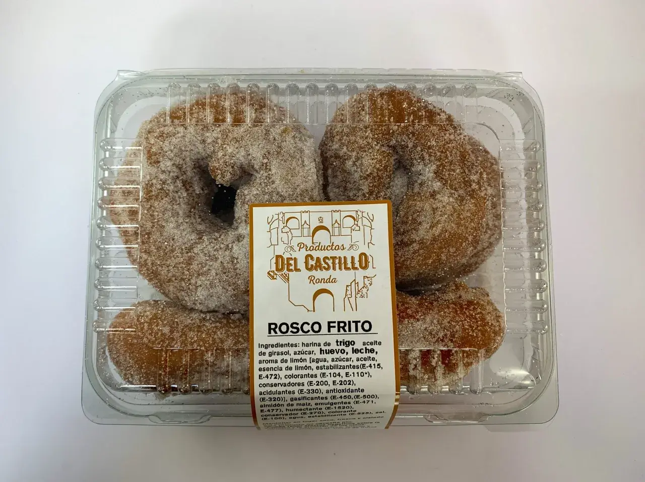 Roscos fritos azucarados en un envase transparente. La etiqueta indica "Productos Del Castillo Ronda" y "Rosco Frito".