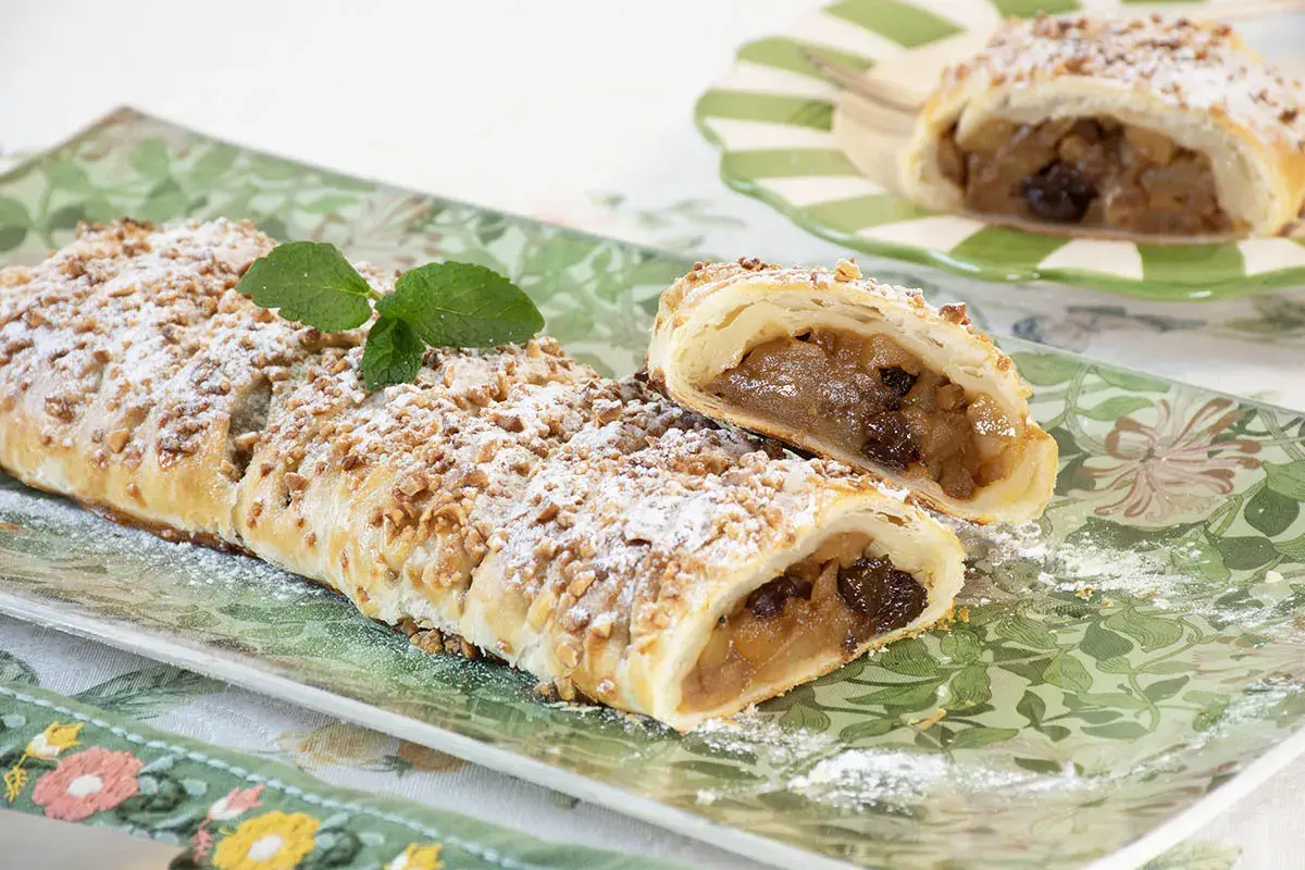 Deliciosa trenza de hojaldre rellena de manzana y pasas, espolvoreada con azúcar glas y nueces picadas.