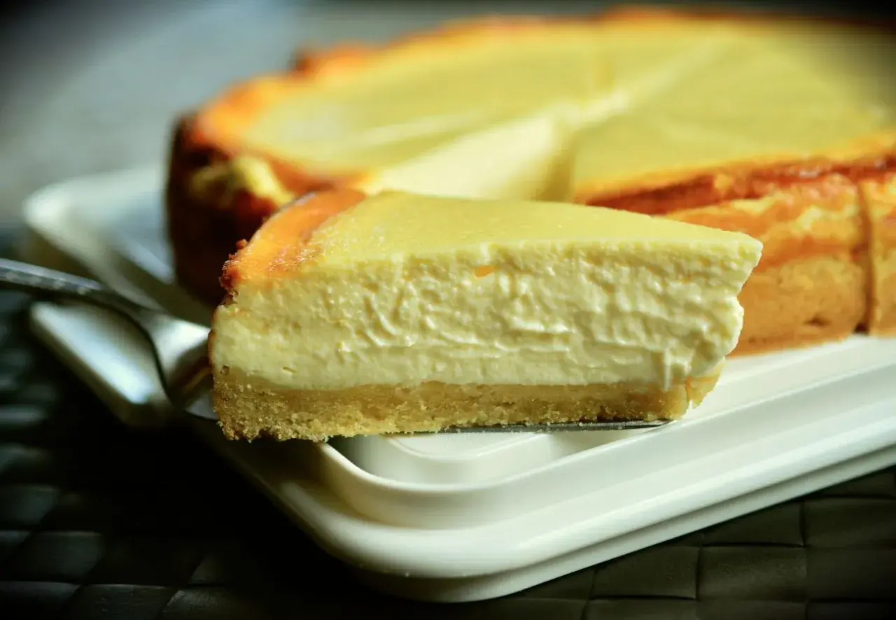 Una rebanada cremosa de tarta de queso Philadelphia, con su base dorada y relleno suave, lista para ser disfrutada.