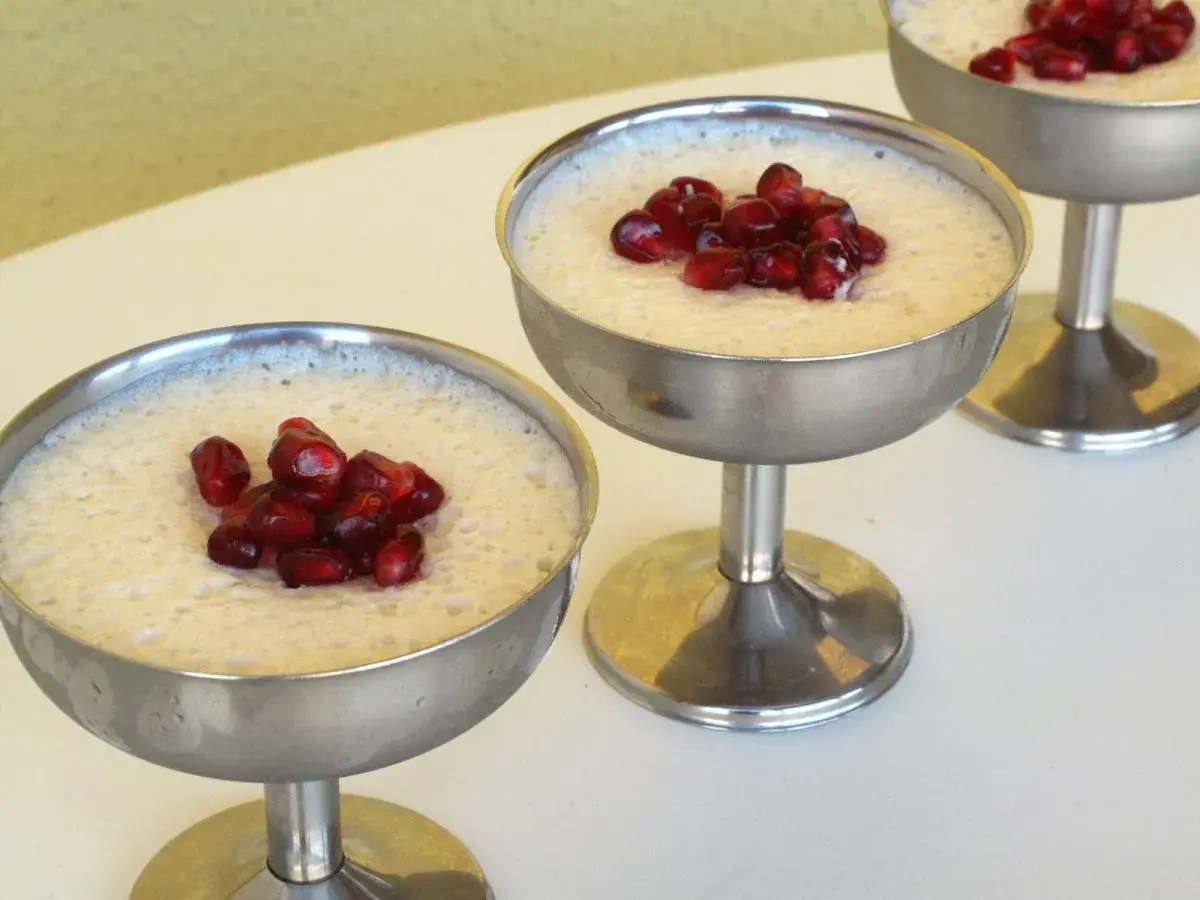 Delicioso mousse de leche condensada Thermomix, coronado con granada, servido en copas metálicas.