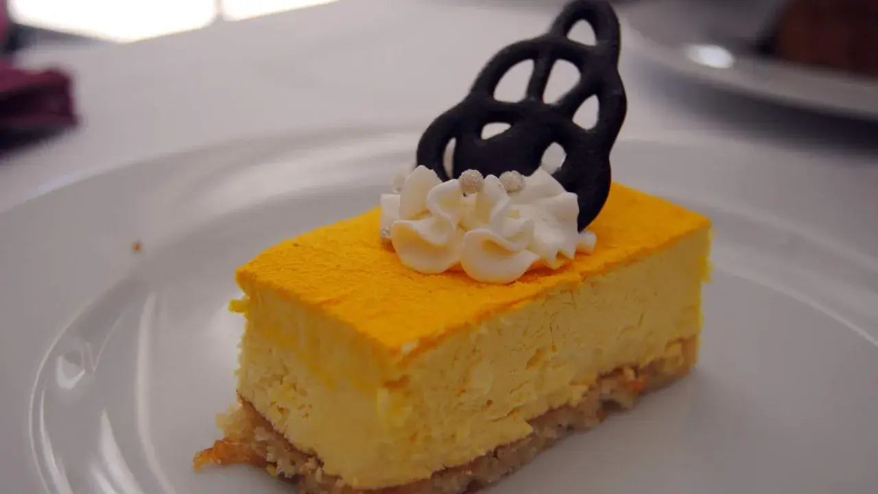 Deliciosa tarta de mango con crema batida y un adorno negro.