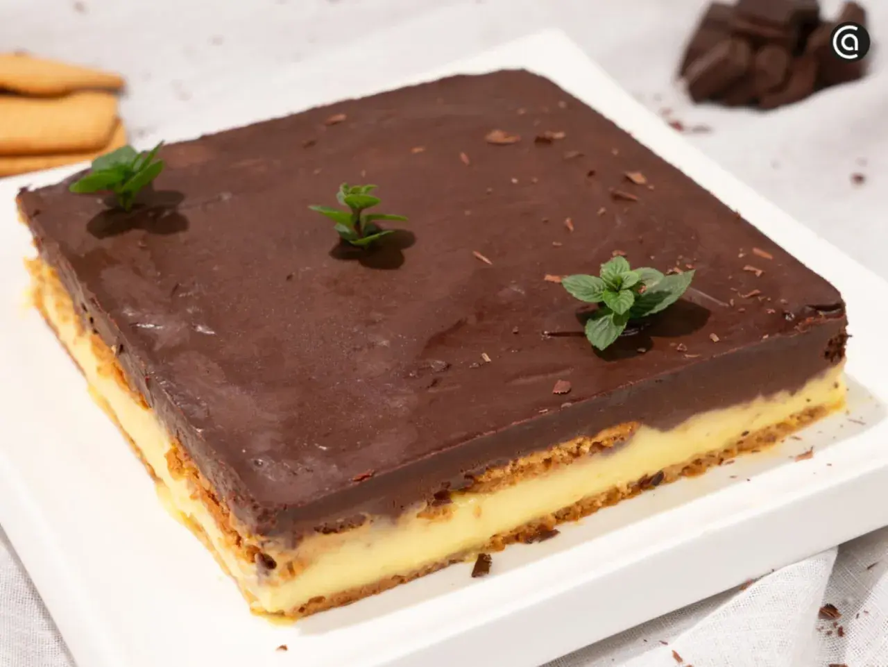 Deliciosa tarta de galletas y chocolate, con capas de crema y cubierta de chocolate brillante, decorada con menta fresca.