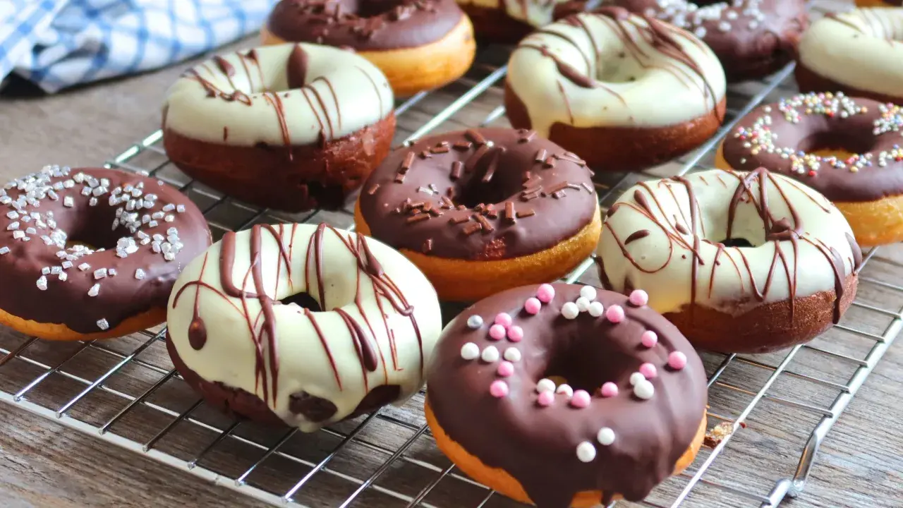 Deliciosos donuts al horno cubiertos de chocolate, glaseado blanco y chispas de colores.