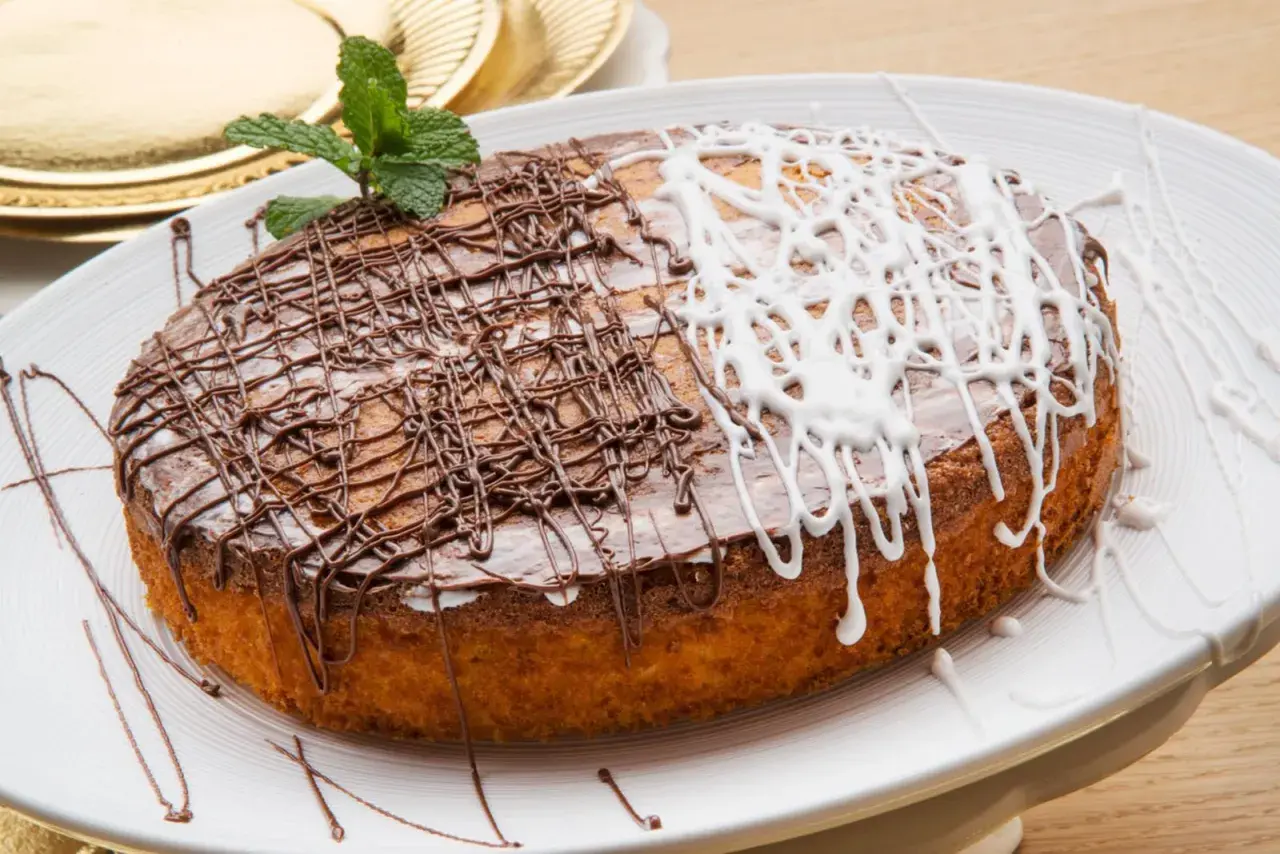 Tarta de zanahoria y coco, decorada con glaseado de chocolate y blanco, y una ramita de menta.