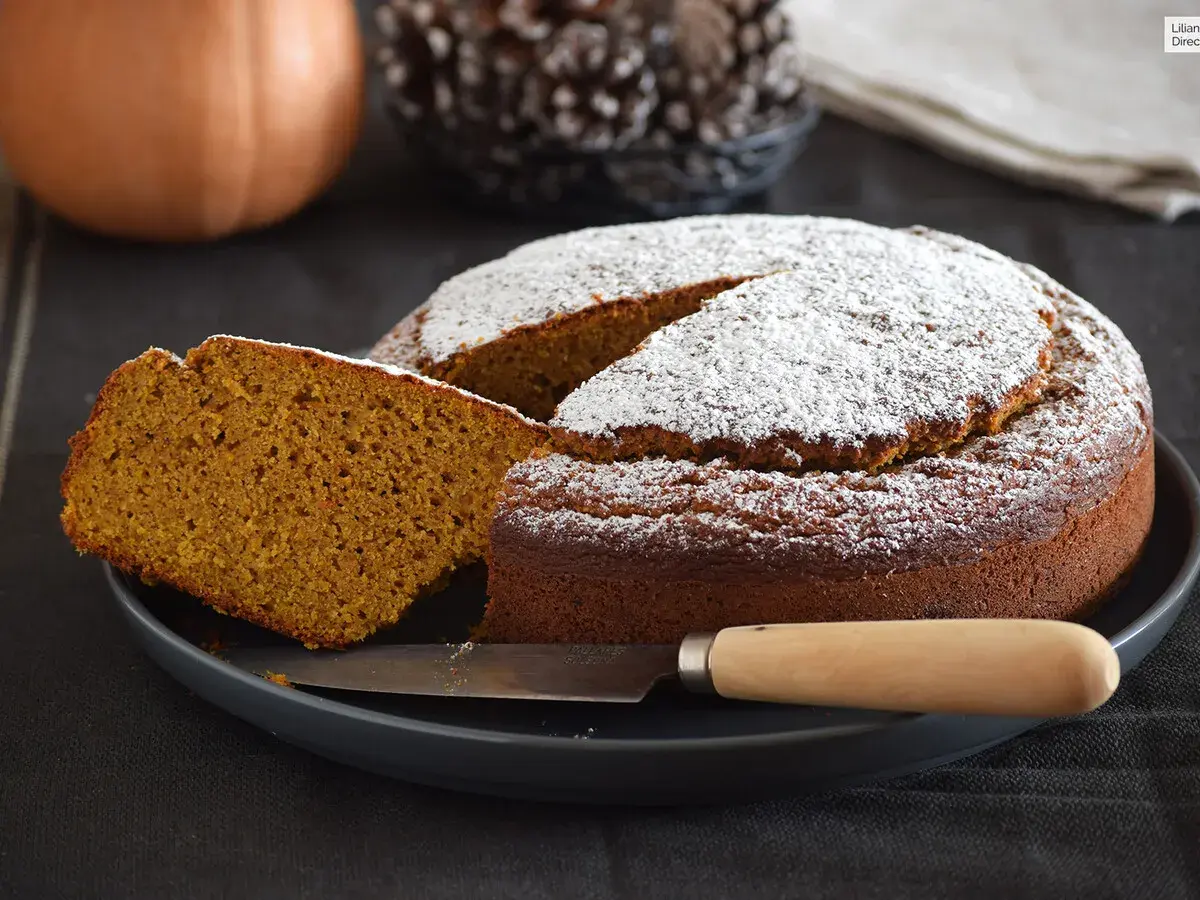 Dos rebanadas de bizcocho de calabaza apiladas, espolvoreadas con azúcar glas, con menta y tenedor.