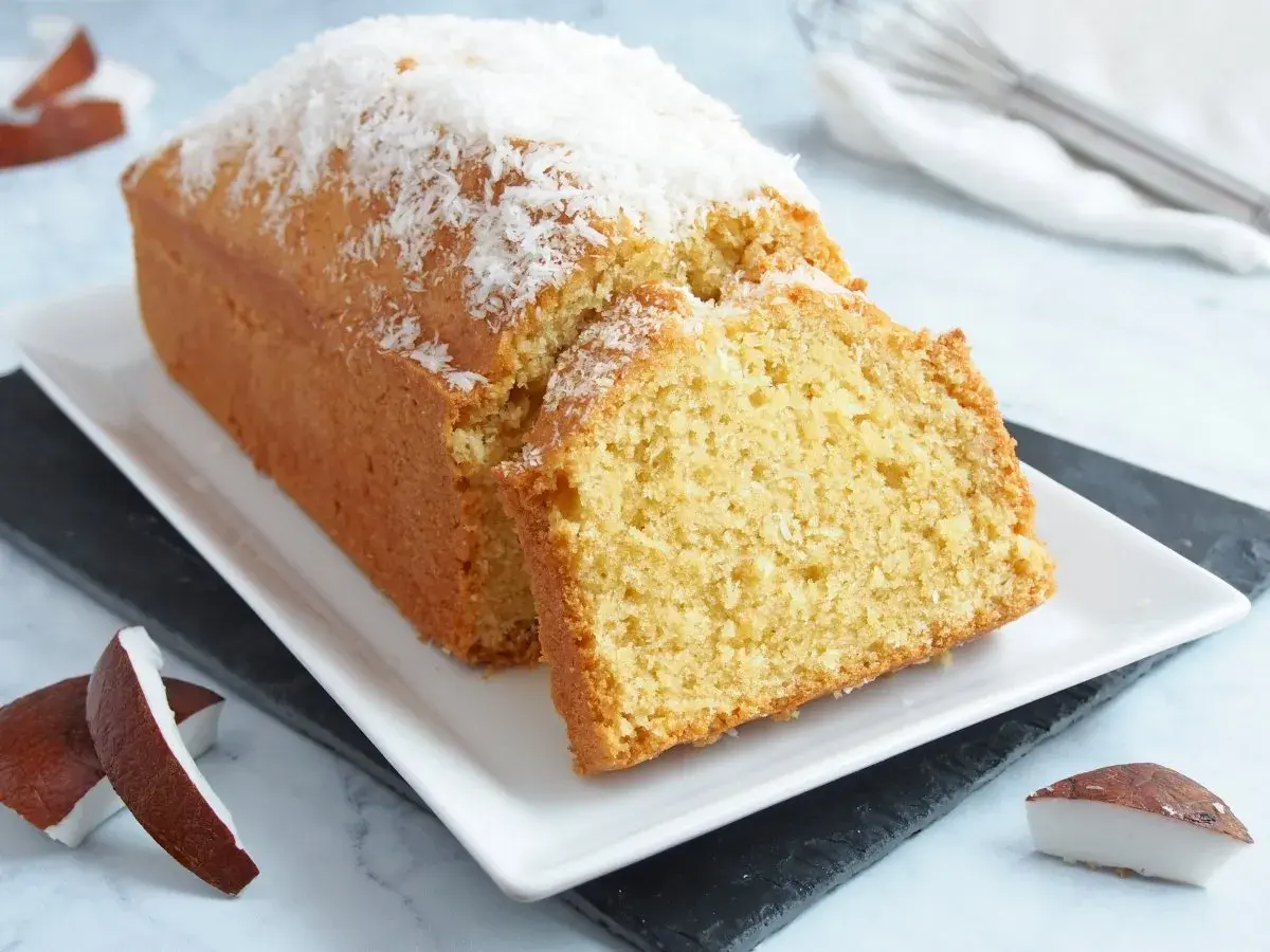 Bizcocho de coco esponjoso, cubierto con coco rallado y acompañado de trozos de coco fresco. ¡Un postre tropical delicioso!