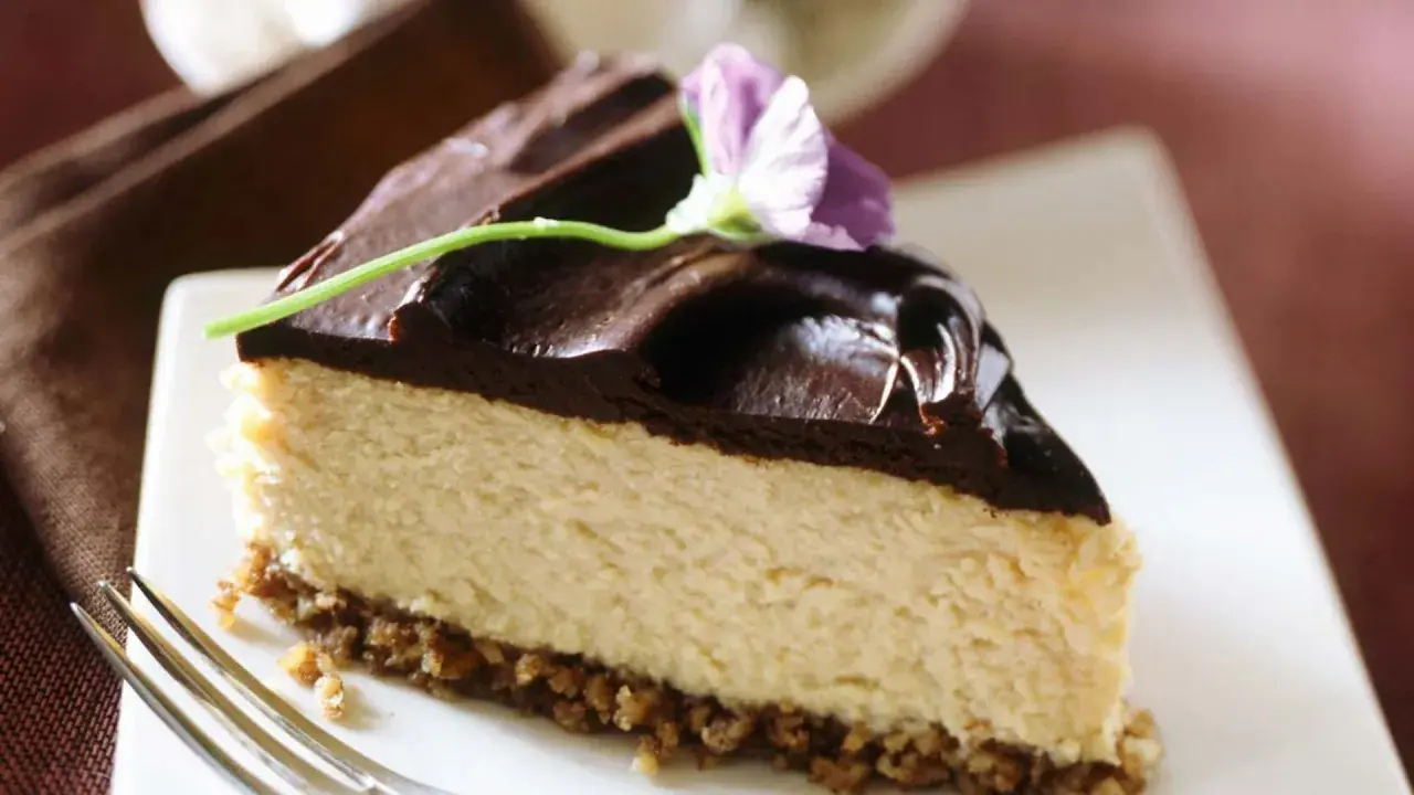 Deliciosa tarta de queso y chocolate, con una capa cremosa y cobertura brillante, decorada con una flor.