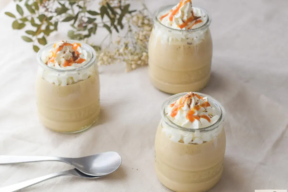 Delicioso mousse de café en vasitos, coronado con crema batida, caramelo y cacao. ¡Perfecto para un postre!