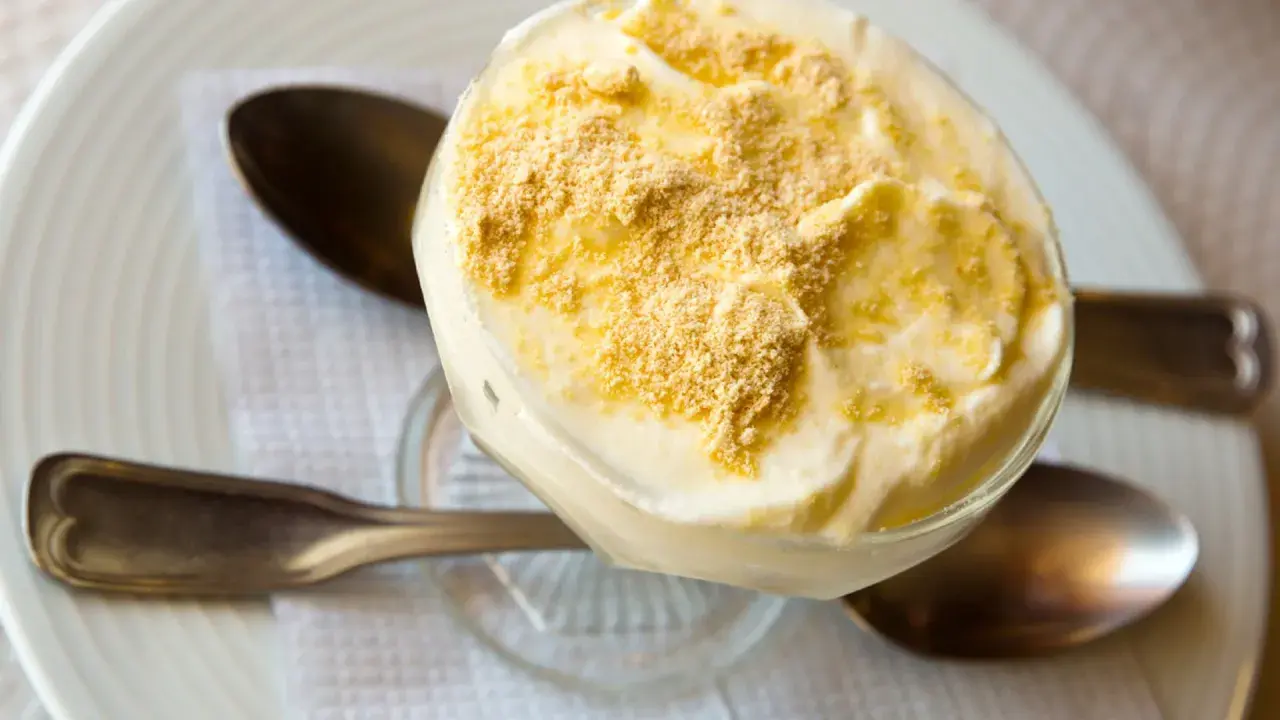 Delicioso postre de serradura portuguesa en copa, cubierto con migas de galleta.